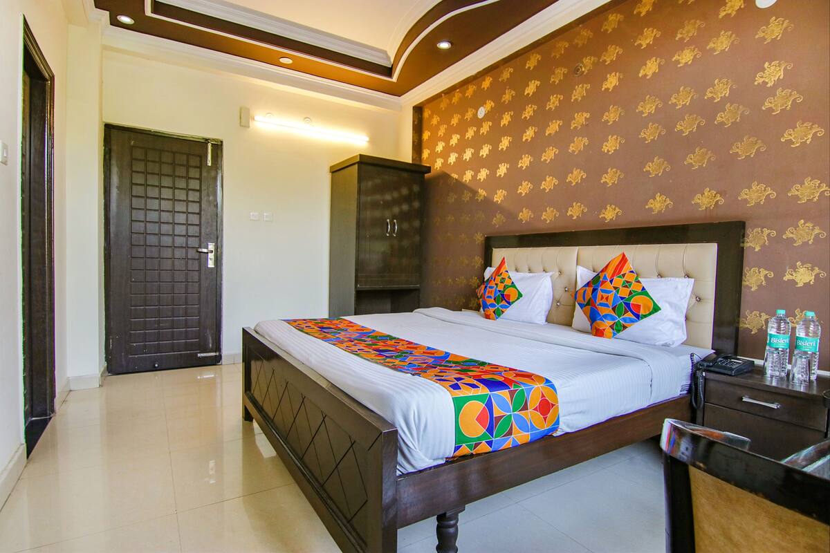 Una habitación de hotel con cama, armario, mesita de noche y puerta al baño.