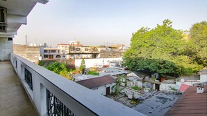 Zona residencial con varios edificios, un árbol y un balcón con barandilla.