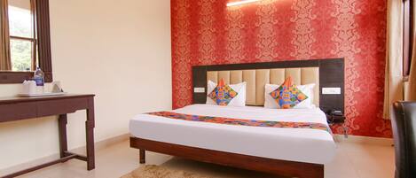 Un dormitorio con una cama grande, una mesita de noche de madera, un espejo y una pared con estampado rojo.