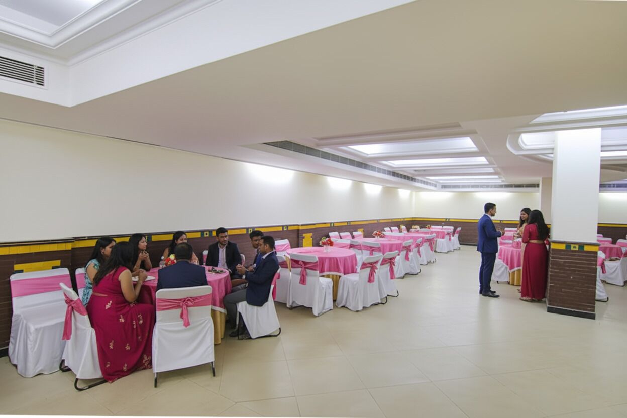 A banquet hall with round tables covered in white tablecloths and pink sashes, arranged in rows.