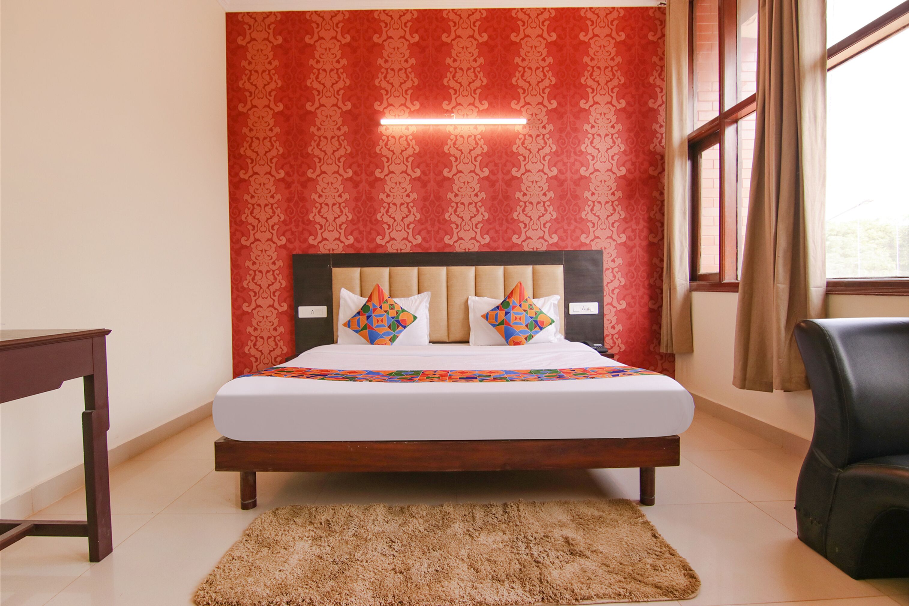 A bedroom with a bed, a desk, a chair, and a window with curtains.