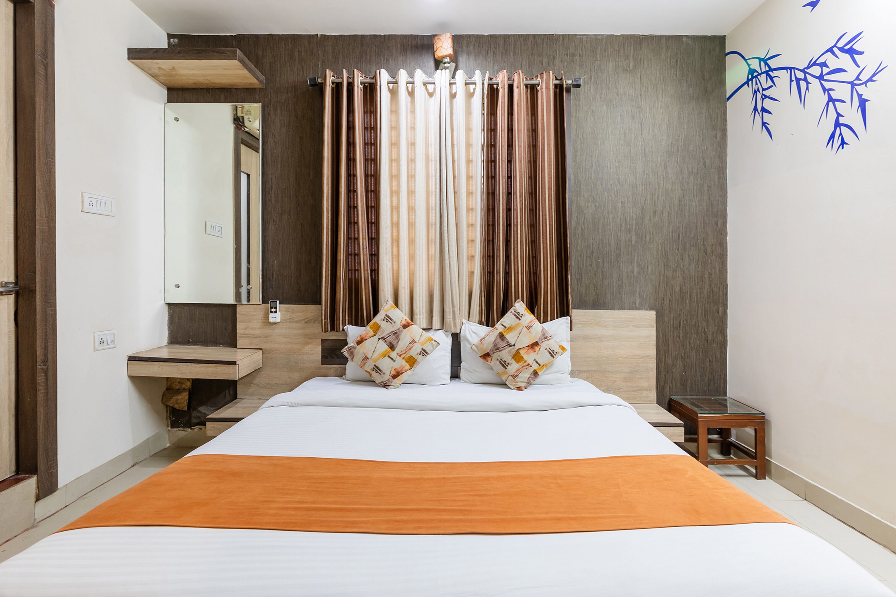 A hotel room with a large bed, a wooden headboard, a bedside table, and a mirror.