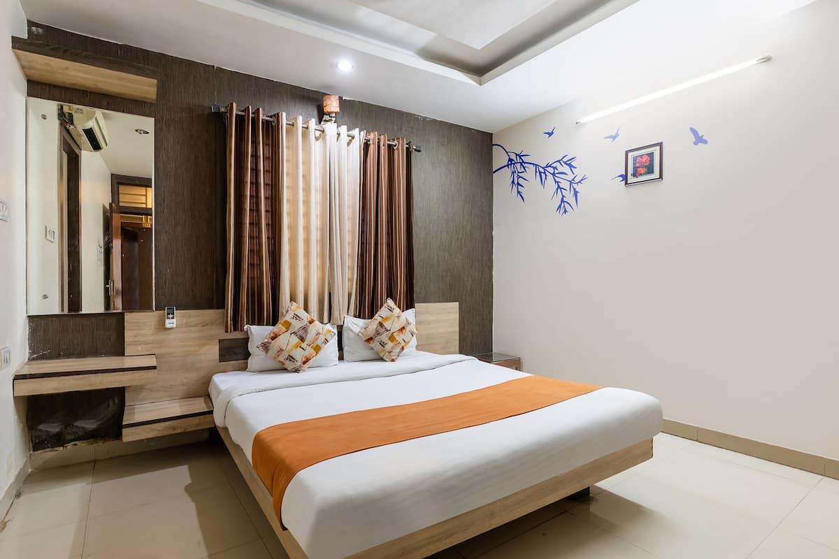 Ein modernes Hotelzimmer mit einem großen Bett, einem Holz-Kopfteil und einem Spiegel.