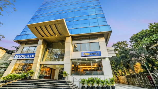 Un hôtel moderne doté d’une façade en verre, d’une entrée imposante avec des marches et d’une signalétique indiquant « Bearing Planet » et « FabHotels ».