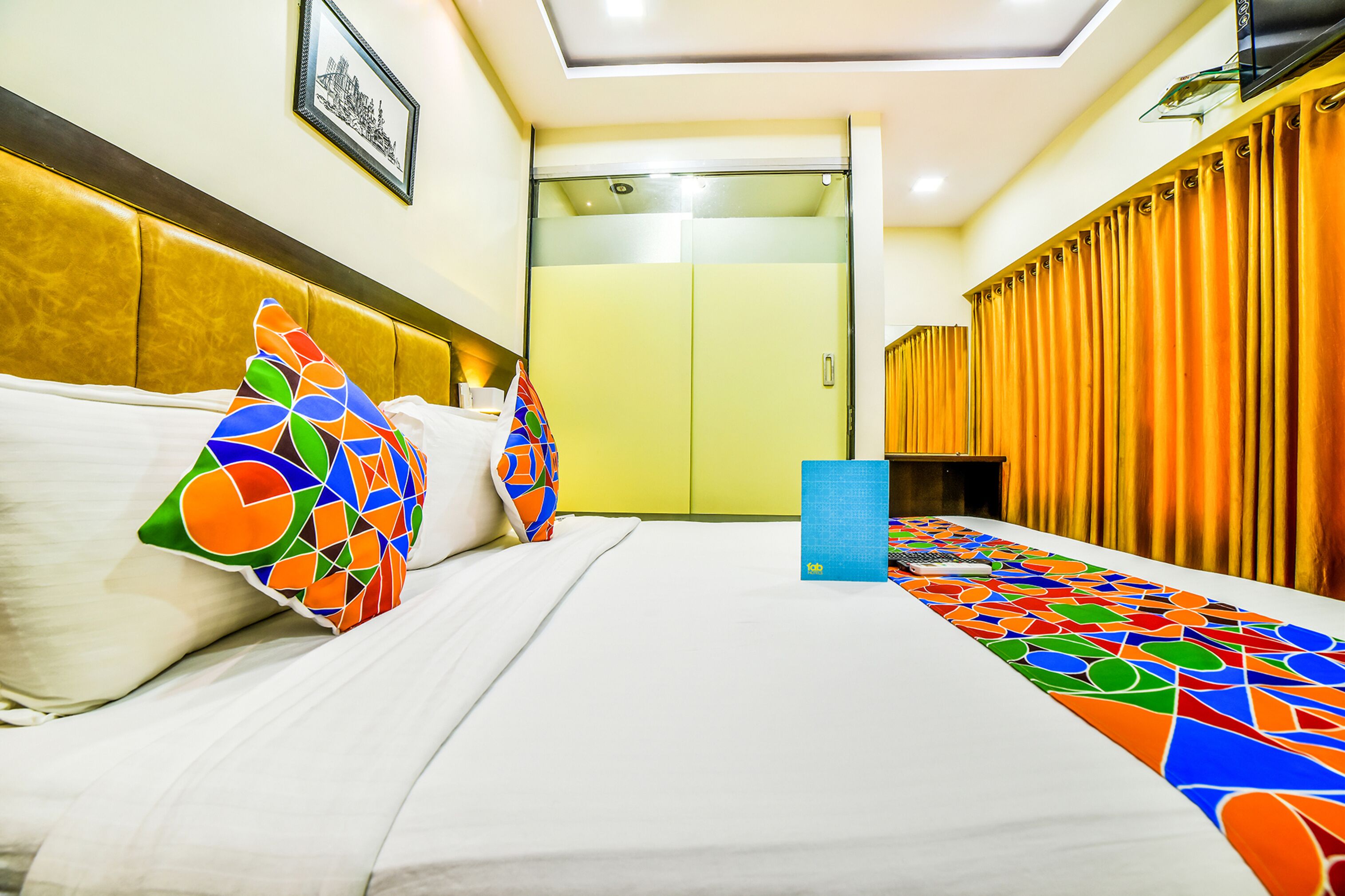 A hotel room with a bed, colorful pillows, a blue tray, and a door leading to a bathroom.