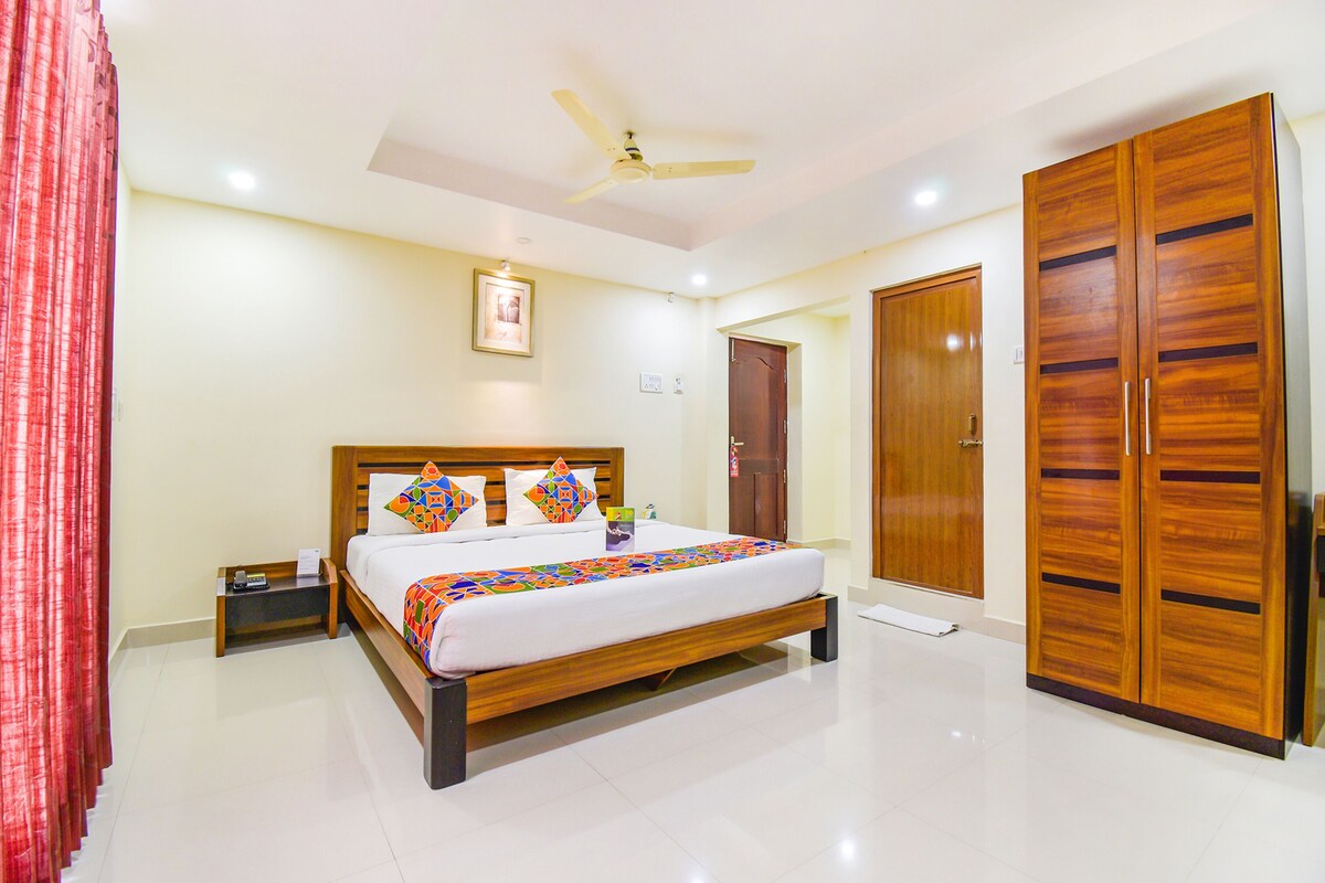 A bedroom with a bed, bedside table, nightstand, wardrobe, and a ceiling fan.