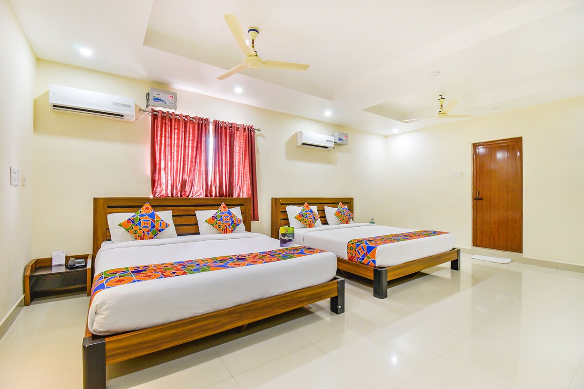 A hotel room with two beds, a ceiling fan, an air conditioning unit, and a wooden door.