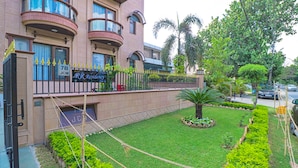 A hotel with a well-maintained garden, a fence, and a sign indicating 'RR Residency'. - Fabhotel Rr Residency (Gurugram)