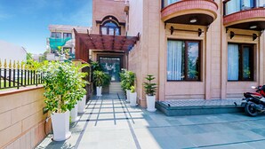 A building with a central entrance, potted plants, and a motorcycle parked outside. - Fabhotel Rr Residency (Gurugram)