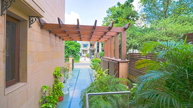A covered outdoor corridor with potted plants and a blue pathway. - Fabhotel Rr Residency (Gurugram)