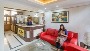A hotel reception area with a receptionist, a red sofa, and a glass coffee table. - FabHotel Altus - DLF CyberHub, Gurugram (Gurugram)