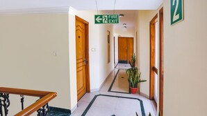 A hotel hallway with a fire exit sign, wooden doors, and a number '2' sign on the wall. - FabHotel Altus - DLF CyberHub, Gurugram (Gurugram)