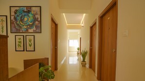A hallway with wooden doors, framed botanical prints, and potted plants. - Fabhotel Gr Lake View (Bengaluru)