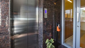 An elevator with a digital display, a push button, and a potted plant beside it. - Fabhotel Gr Lake View (Bengaluru)