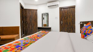 Une chambre d’hôtel avec un lit, un canapé, un miroir et des armoires en bois.