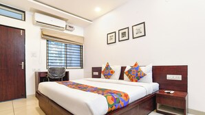 A hotel room with a large bed, a desk, and a chair. There are three framed pictures on the wall.