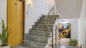 A staircase with granite steps and metal railings, a wooden door with a sign, and a painting on the wall. - Fabhotel Surbhi (Bhopal)