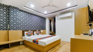 A modern bedroom with a wooden bed, a desk, and a patterned wall. - Fabhotel Surbhi (Bhopal)