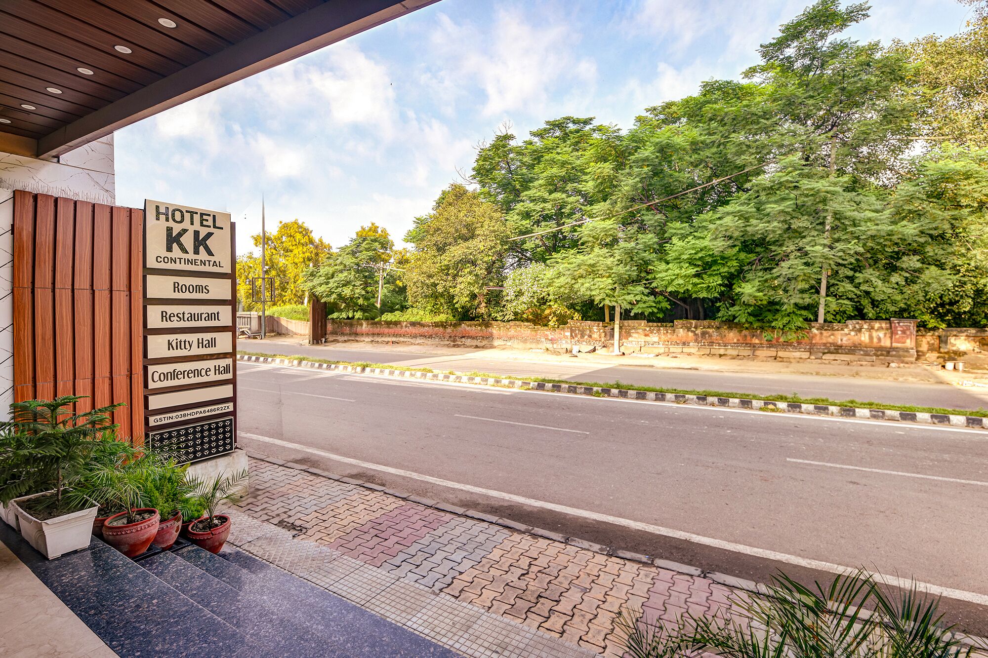 A hotel entrance with a sign listing amenities like rooms, a restaurant, a kitty hall, and a conference hall.
