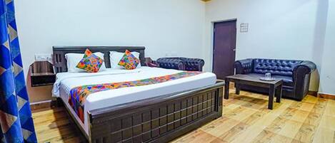 Quarto com cama, mesa de cabeceira, sofá e porta.