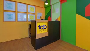 Un comptoir d’accueil avec une enseigne indiquant « fab hotels », des œuvres d’art encadrées accrochées au mur et un motif géométrique sur le mur.