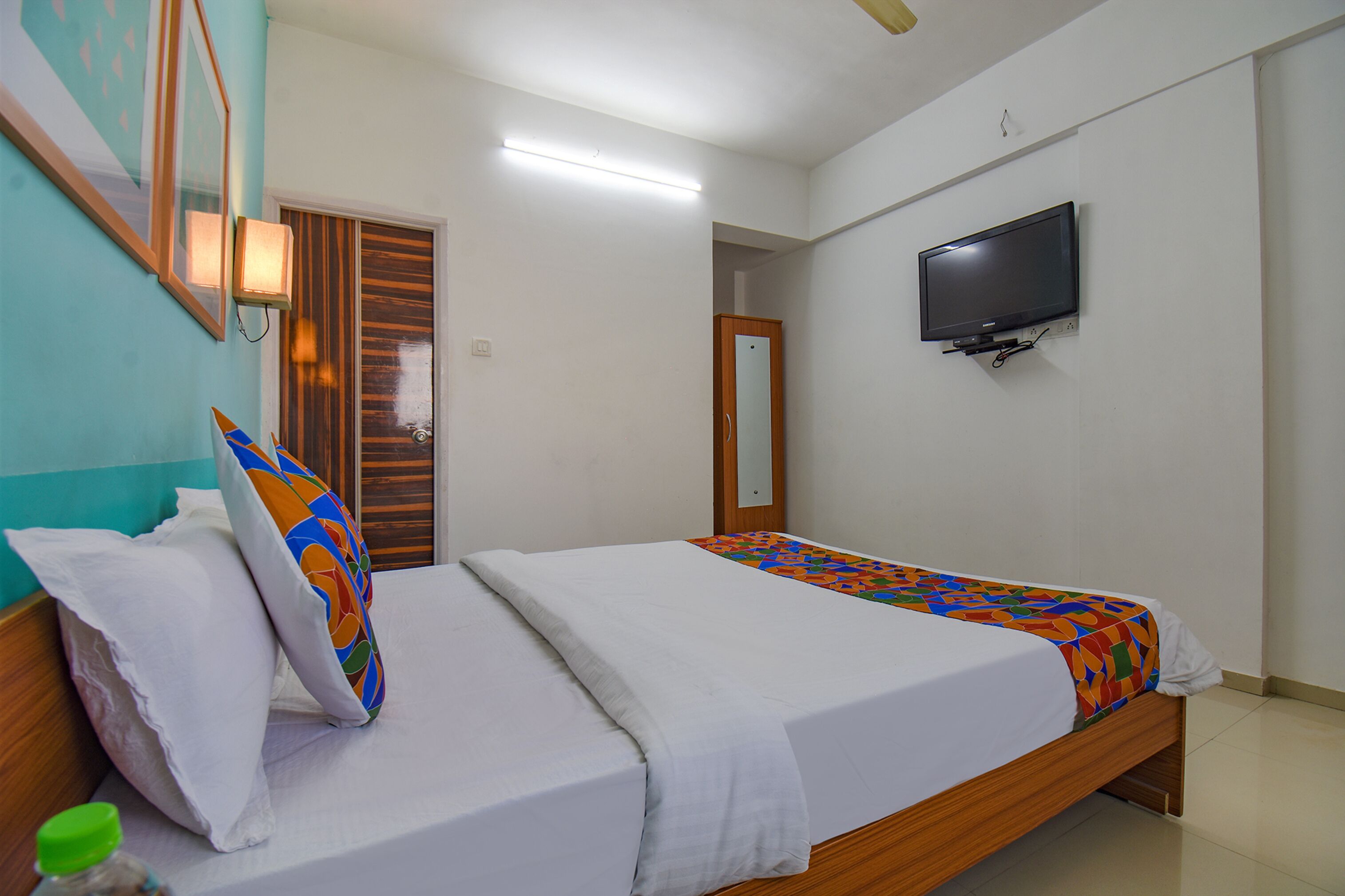 A bedroom with two beds, a television mounted on the wall, and a wooden door.