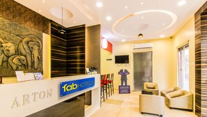 A modern hotel lobby with a reception desk, seating area, and a large wall mural. - Fabhotel Arton Suite (Mumbai)