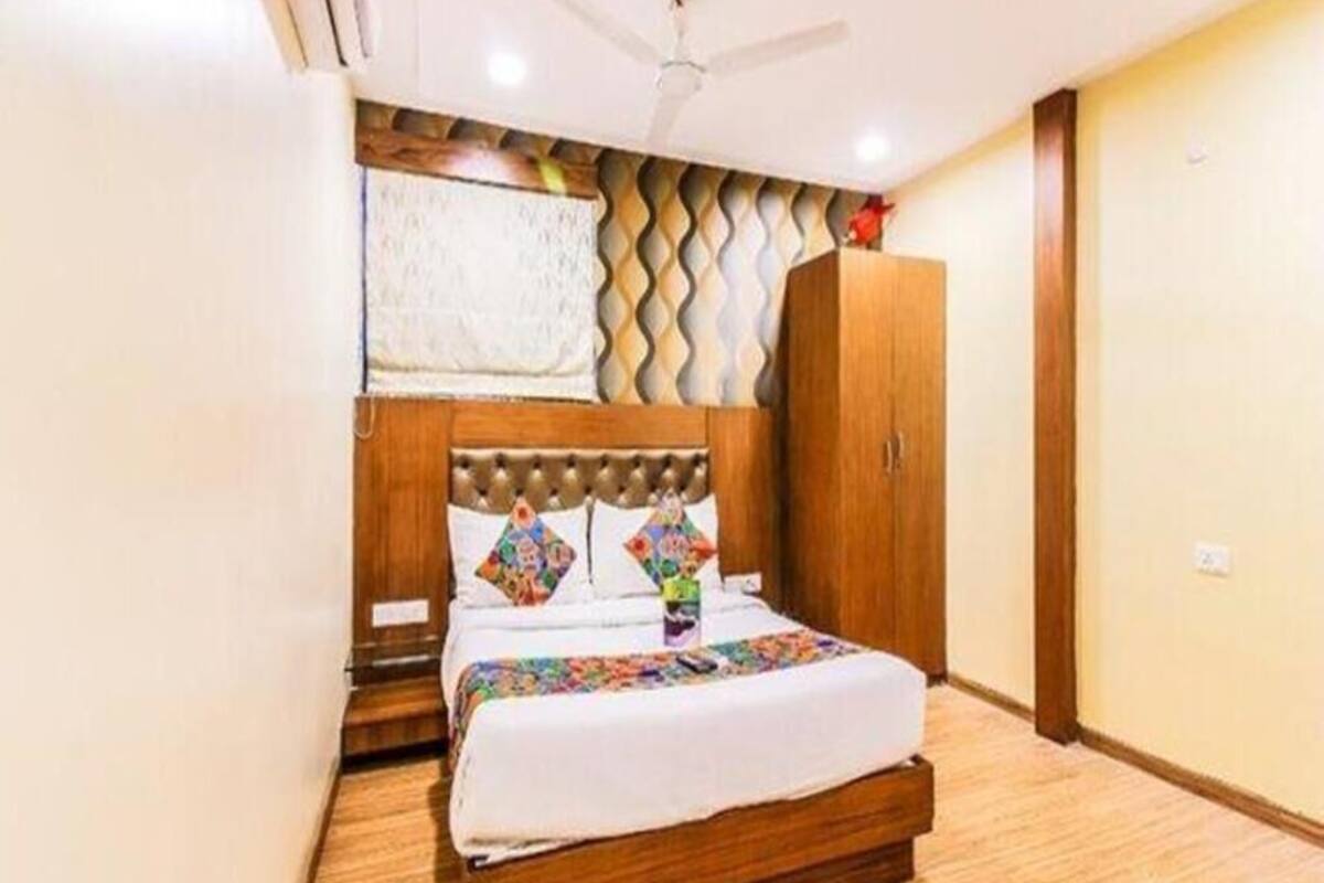 Une chambre à coucher avec une tête de lit en bois, un lit recouvert d’une courtepointe blanche, un ventilateur de plafond et une armoire.
