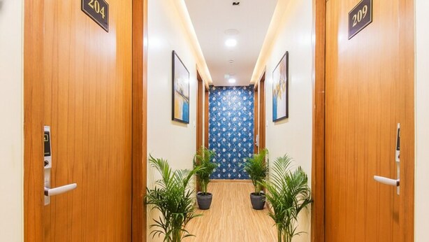 A hotel hallway with wooden doors numbered 204 and 209, potted plants, and framed pictures on the walls. - Fabhotel Arton Suite (Mumbai)
