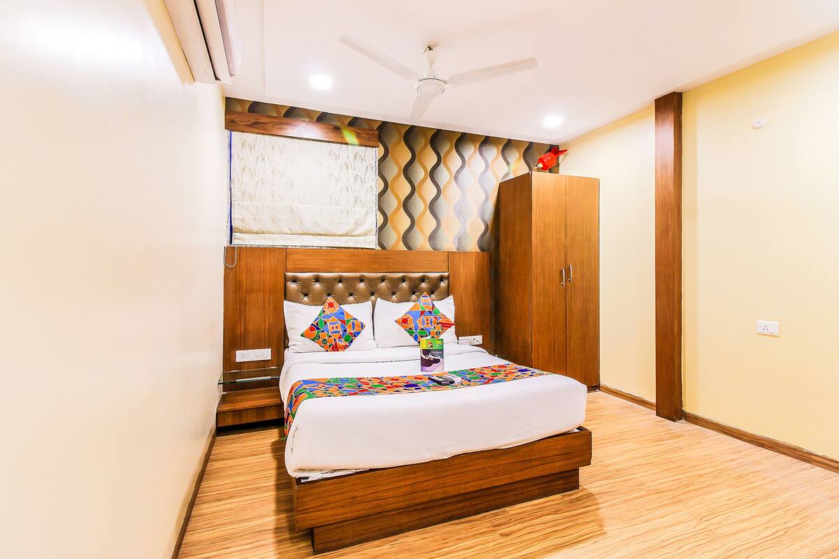 Une chambre à coucher avec un lit en bois, un ventilateur de plafond et une armoire.