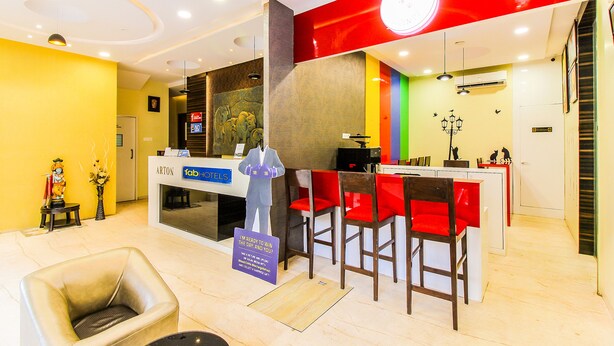 A hotel reception area with a modern design, including a reception desk, a waiting area with chairs, and a visible staircase. - Fabhotel Arton Suite (Mumbai)