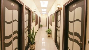 Pasillo de hotel con puertas numeradas 206 al 207, plantas en macetas e iluminación en la pared.