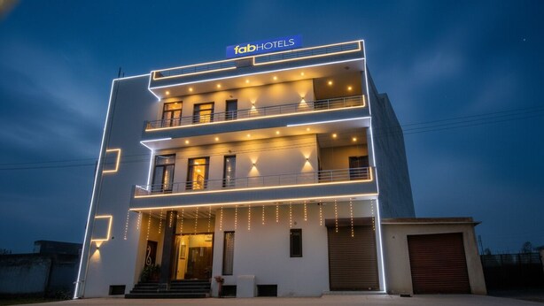 Un edificio de varios pisos con un diseño moderno, que destaca un cartel prominente de 'fabHOTELS' en la parte superior.