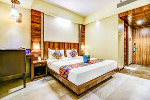 A hotel room with a large bed, wooden headboard, bedside tables, and a desk with a lamp. - Fabhotel Crawford Inn (Mumbai)