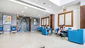 A hotel lobby with blue seating, a Buddha painting, and a large decorative panel. - FabHotel Aay Kay (Amritsar)