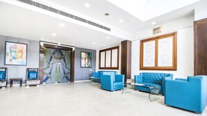 A spacious lobby with blue seating, a large glass door, and artwork on the walls. - FabHotel Aay Kay (Amritsar)