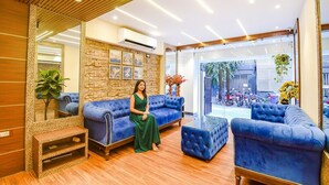 A modern lobby with a stone wall, a large mirror, and blue upholstered seating. - FabHotel Lake View Topsia (Kolkata)