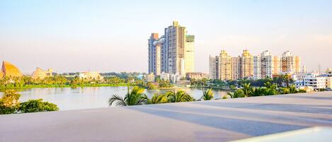 A modern hotel with a rooftop pool overlooking a cityscape and a body of water.