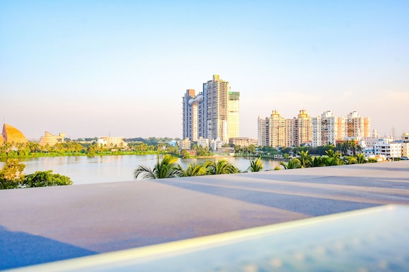 A modern hotel with a rooftop pool overlooking a cityscape and a body of water.
