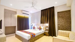 A modern hotel room with a bed, bedside table, chair, and a ceiling fan. - FabHotel Lake View Topsia (Kolkata)