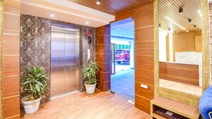 A modern elevator with a geometric wall design, two potted plants, and a wooden ceiling. - FabHotel Lake View Topsia (Kolkata)