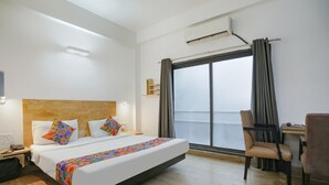 A hotel room with a large bed, a desk, a chair, and a window with curtains. - FabHotel F9 Noida Sector 51 (Noida)