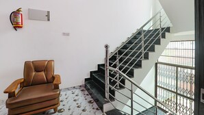 A staircase with metal railings, a fire extinguisher on the wall, and a patterned floor. - FabHotel Lumbini International (Varanasi)