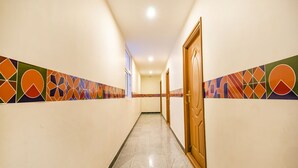 A hallway with patterned walls and a tiled floor, leading to a door. - Fabhotel Thejas Paaradise (Coimbatore)