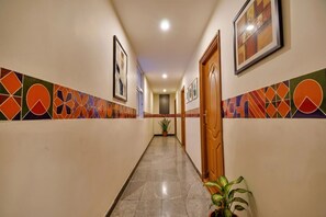 A hallway with patterned walls, a potted plant, and a door. - Fabhotel Thejas Paaradise (Coimbatore)