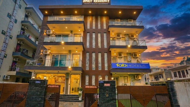Un edificio de varios pisos con un diseño arquitectónico moderno, que presenta balcones y una entrada destacada.