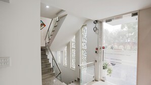 Un interior limpio y moderno con una escalera, barandilla de vidrio y una puerta que da a un espacio exterior.