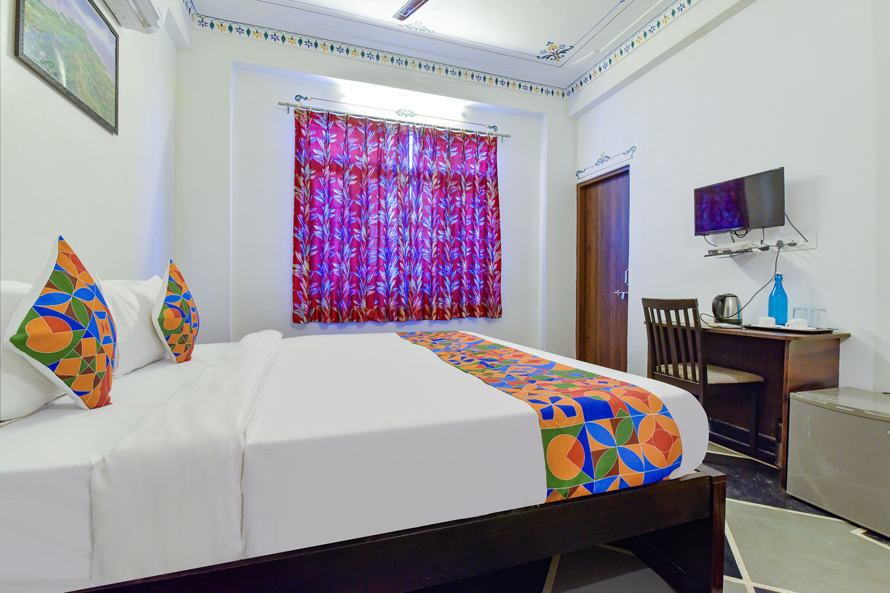 Una habitación de hotel con cama, televisión, escritorio y silla.