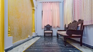A room with a marble floor, a wooden bench, a small table, and pink curtains. - Fabhotel The Castle Homestay I (Udaipur)