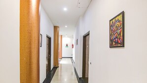 A hallway with a polished floor, white walls, and a framed artwork on the right. - Fabhotel Citi Inn (Dera Bassi)